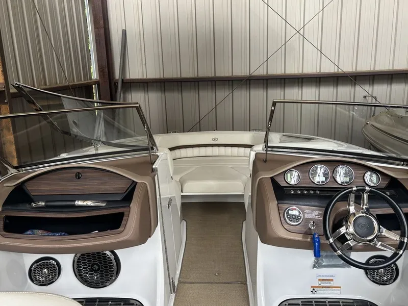 Slide: The Image of 2014 Cobalt A25 boat interior with dashboard and seating, stored in a metal shed. - 11