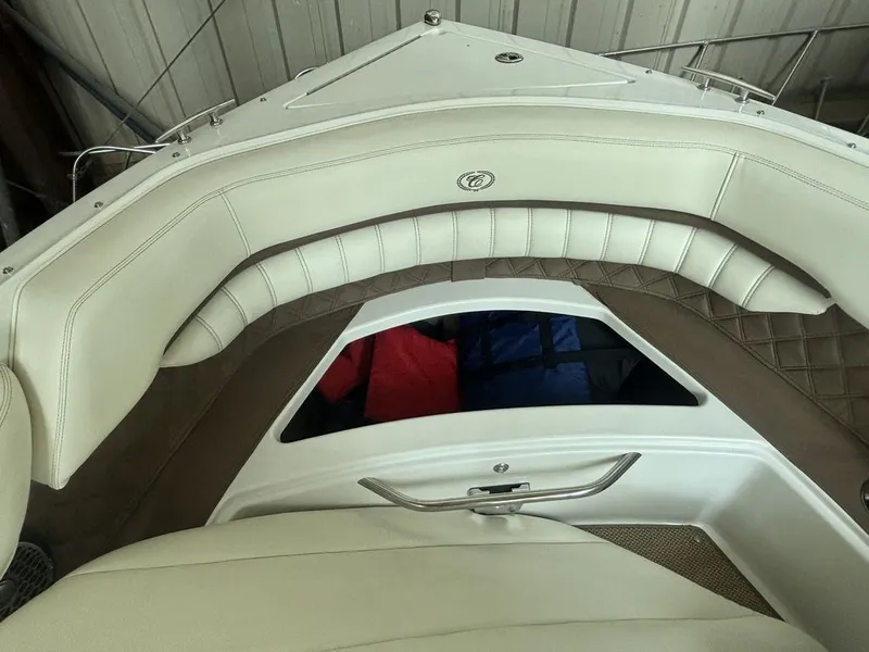Slide: The Image of 2014 Cobalt A25 boat interior with white leather seating and storage compartment. - 19