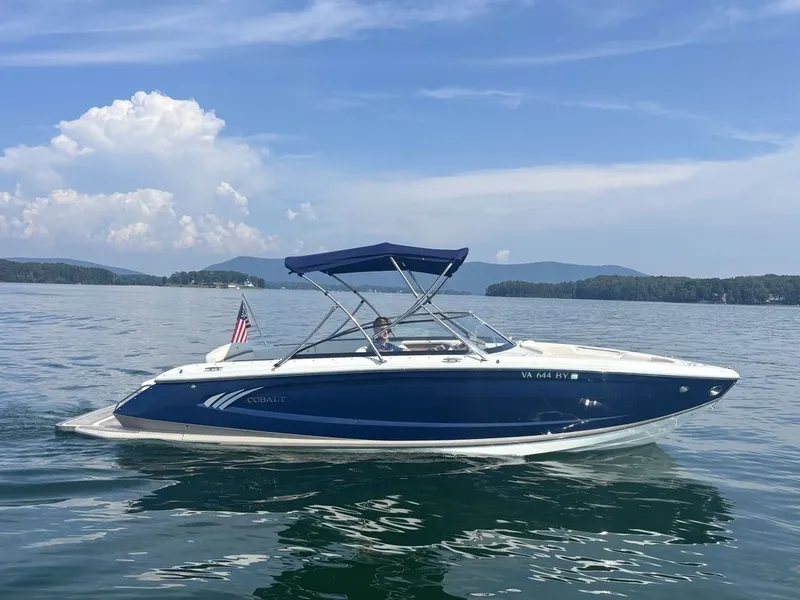 Slide: The Image of 2014 Cobalt A25 boat on a serene lake with mountains in the background. - 2