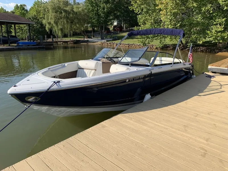 Slide: The Image of 2014 Cobalt A25 boat docked on a sunny lake with lush greenery. - 3