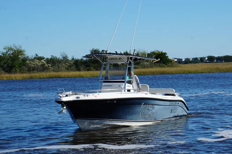 The Image of 2006 Century 2600 Center Console boat cruising on a calm river under clear blue skies. - 1