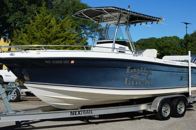 Slide: The Image of 2006 Century 2600 Center Console boat on trailer, named "Lotta Luck," parked outdoors. - 5