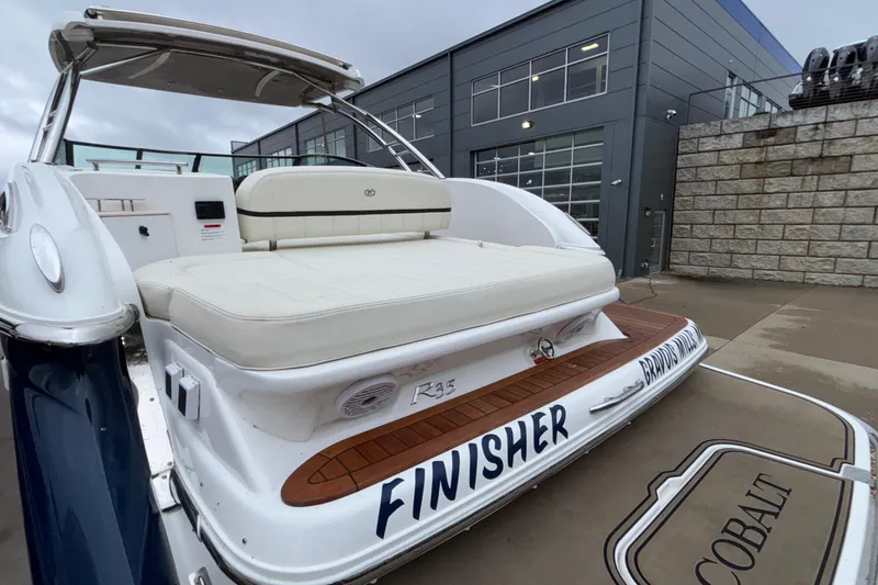 Slide: The Image of 2022 Cobalt R35 boat with white seating, docked near a modern building. - 12