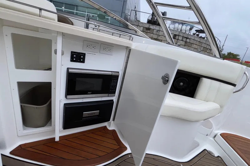 Slide: The Image of 2022 Cobalt R35 boat interior with microwave, storage, and seating on teak flooring. - 27
