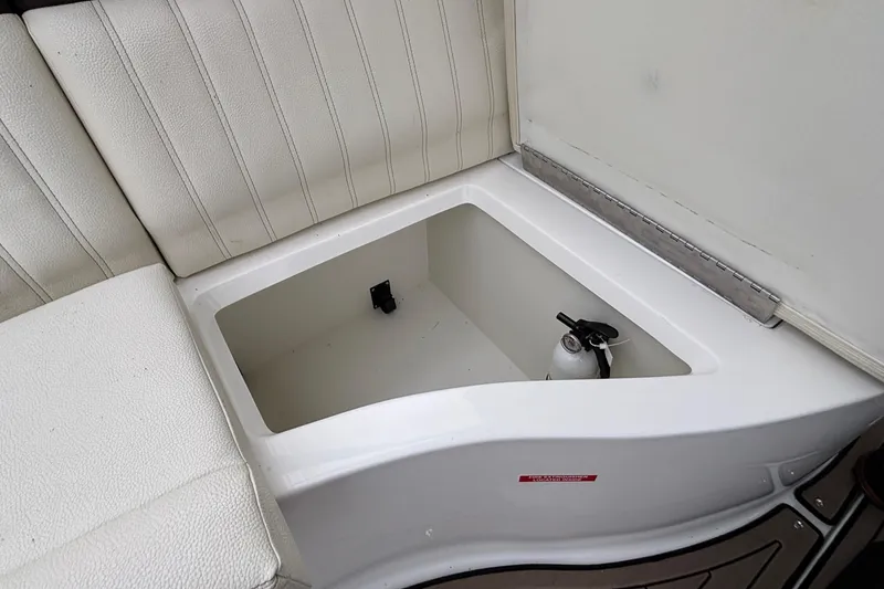 Slide: The Image of 2022 Cobalt R35 boat storage compartment with fire extinguisher, white cushioned seating. - 36