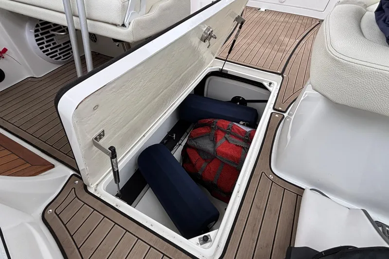 Slide: The Image of Open storage compartment on 2022 Cobalt R35 boat with cushions and a red bag. - 54