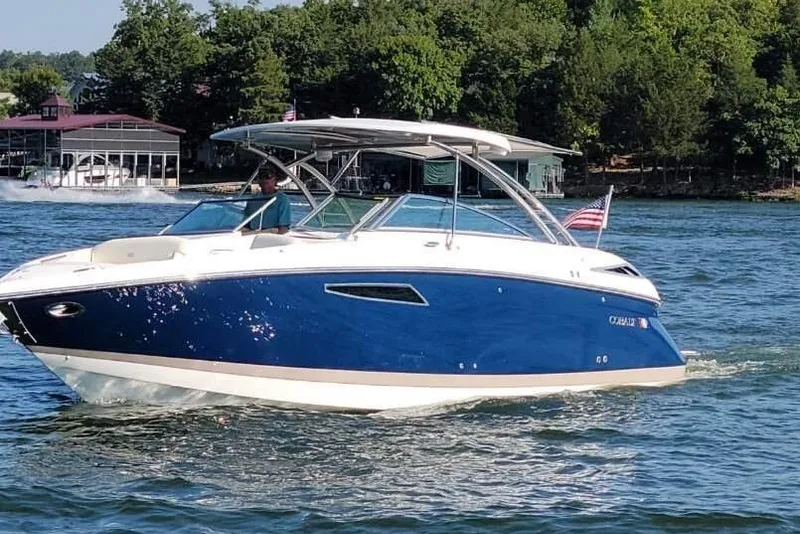 Slide: The Image of 2022 Cobalt R35 boat cruising on a lake with lush green trees in the background. - 55