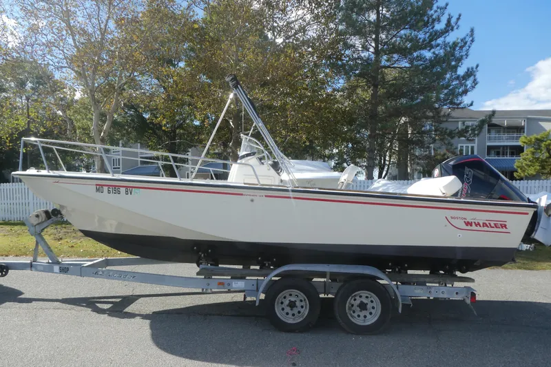 Slide: The Image of 1989 Boston Whaler 220 Outrage boat on trailer, parked outdoors. - 13