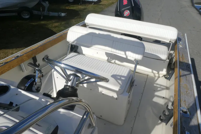 Slide: The Image of 1989 Boston Whaler 220 Outrage boat interior with white seating and steering wheel. - 9