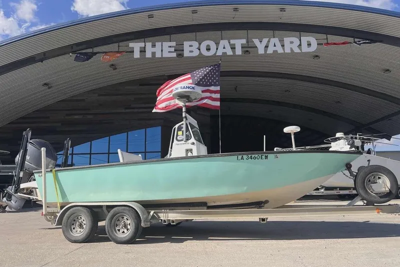 Slide: The Image of 1997 Gravois 20CC boat on trailer with American flag, under clear blue sky. - 2