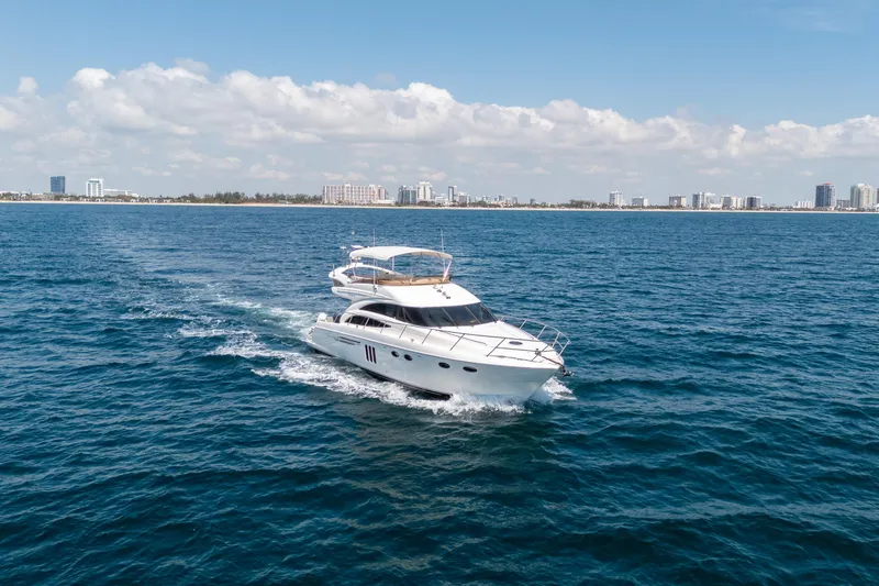 Slide: The Image of 2008 Princess 58 Flybridge yacht cruising on open water with city skyline in background. - 2