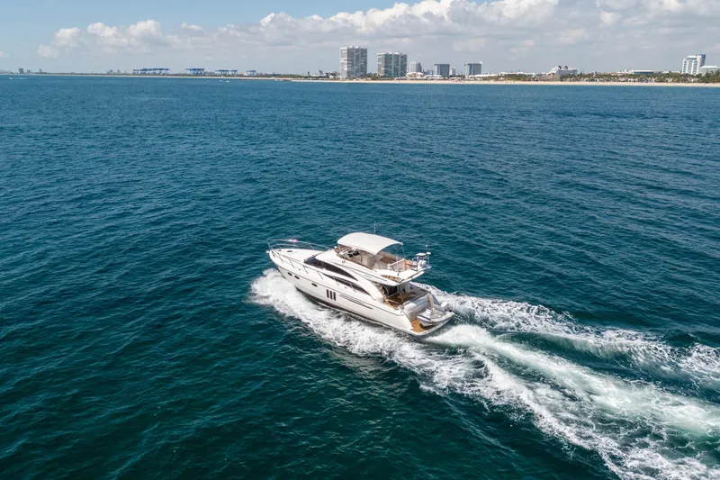 Slide: The Image of 2008 Princess 58 Flybridge yacht cruising on open sea near city skyline. - 5