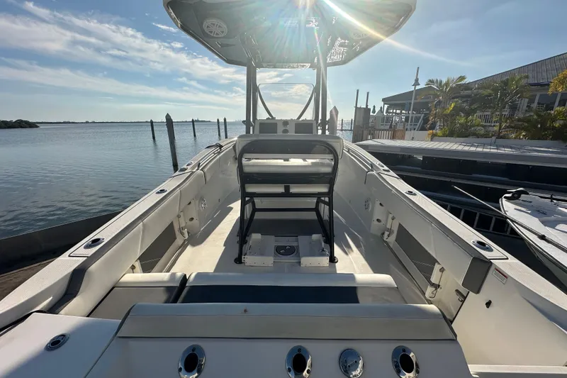 Slide: The Image of 2018 Blackfin 212 CC boat interior with seating, docked by calm waters under a sunny sky. - 15