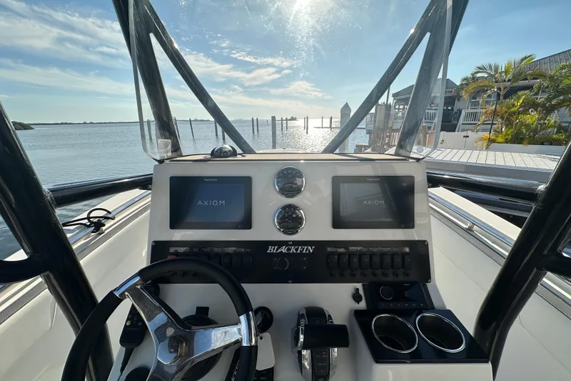 Slide: The Image of 2018 Blackfin 212 CC boat dashboard with dual Axiom displays, steering wheel, and scenic water view. - 28