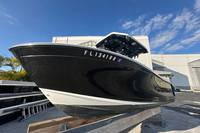 Slide: The Image of 2018 Blackfin 212 CC boat on display, black hull, sunny day, industrial background. - 3