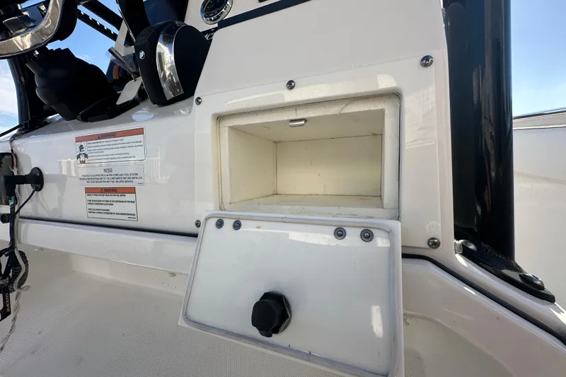 Slide: The Image of 2018 Blackfin 212 CC boat console with open storage compartment and warning labels. - 44