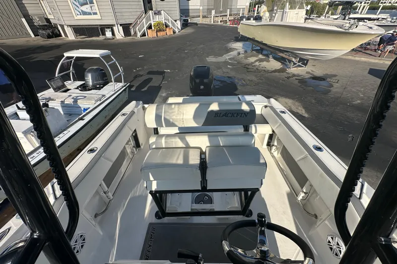 Slide: The Image of 2018 Blackfin 212 CC boat interior with seating and steering wheel, docked at marina. - 64