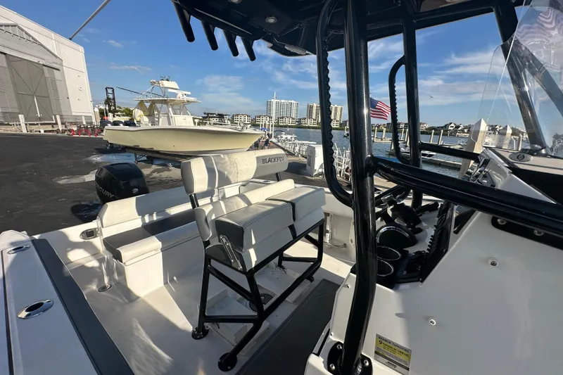Slide: The Image of 2018 Blackfin 212 CC boat docked, featuring seating and control area, with waterfront view. - 66