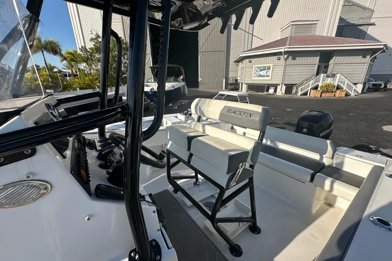 Slide: The Image of 2018 Blackfin 212 CC boat interior with seating and controls, docked near a building. - 67