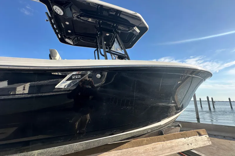 Slide: The Image of 2018 Blackfin 212 CC boat docked, featuring sleek black hull and T-top under clear sky. - 7