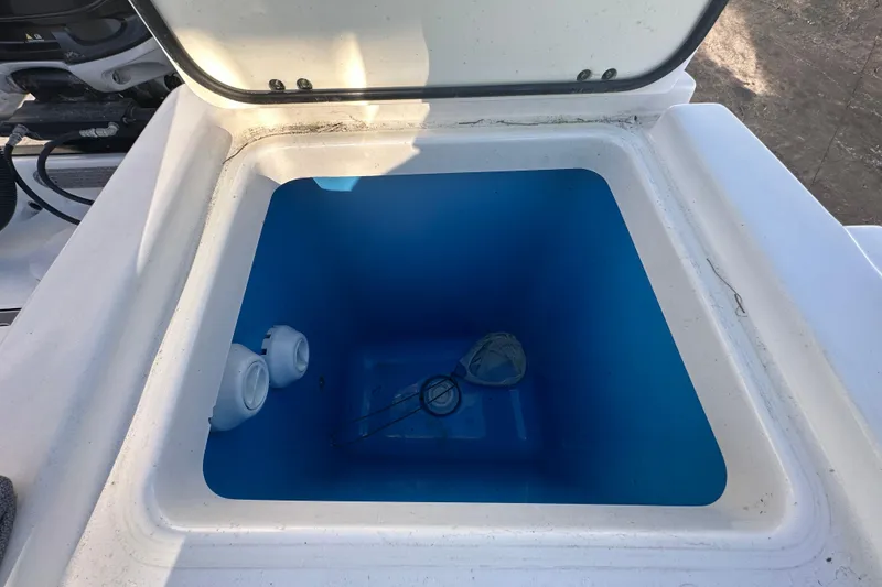 Slide: The Image of Open storage compartment on 2018 Blackfin 212 CC boat, featuring a blue interior. - 80
