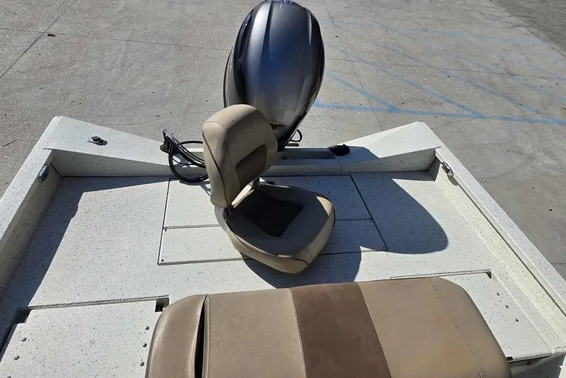 Slide: The Image of 2019 Xpress H20B Bay boat interior with seating and motor, parked on concrete. - 10