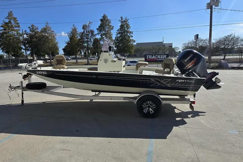 Slide: The Image of 2019 Xpress H20B Bay boat on trailer, parked outdoors under clear sky. - 6