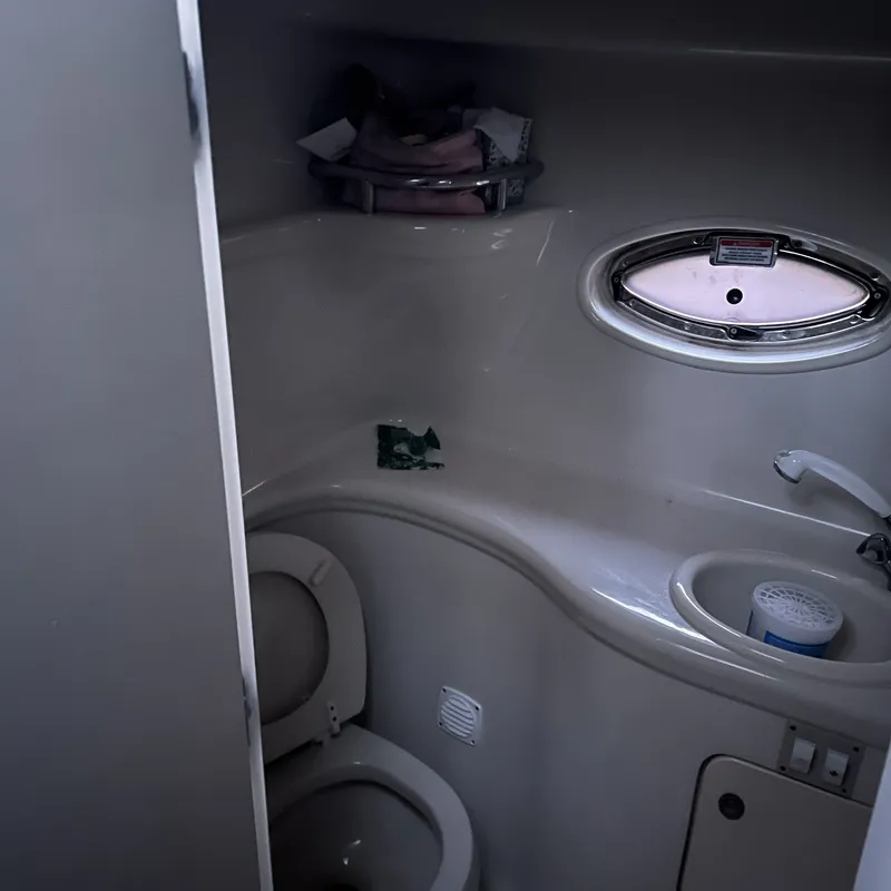 Slide: The Image of 2005 Sea Ray 290 Amberjack boat bathroom with toilet, sink, and porthole window. - 11