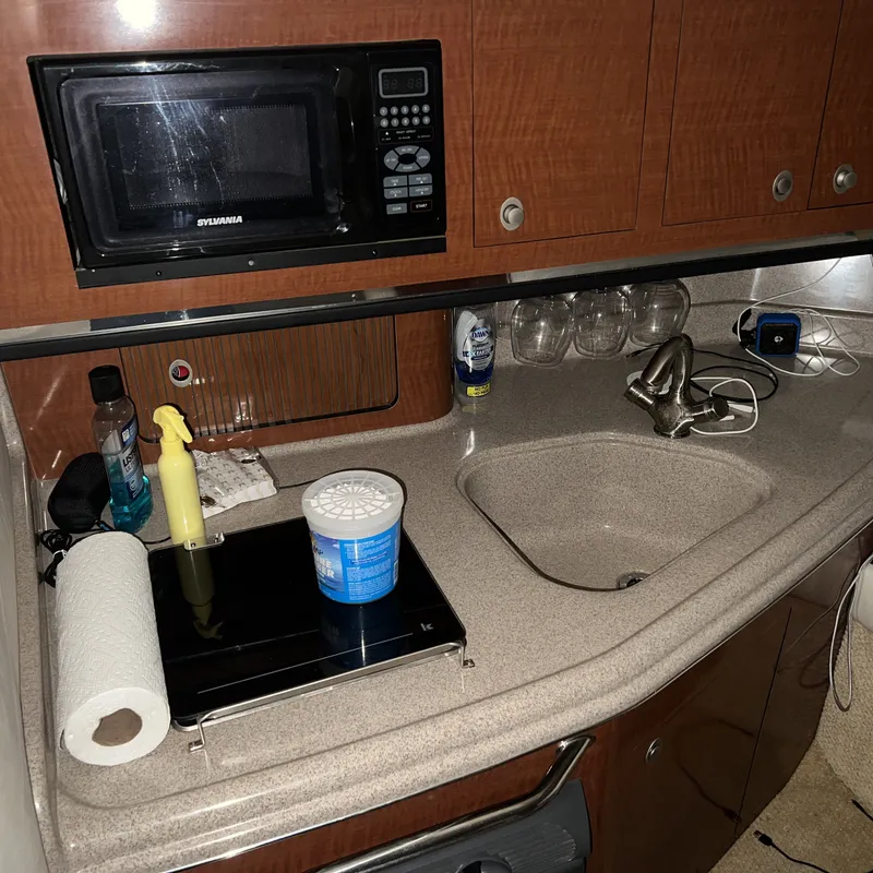 Slide: The Image of 2005 Sea Ray 290 Amberjack kitchen area with microwave, sink, and countertop essentials. - 12
