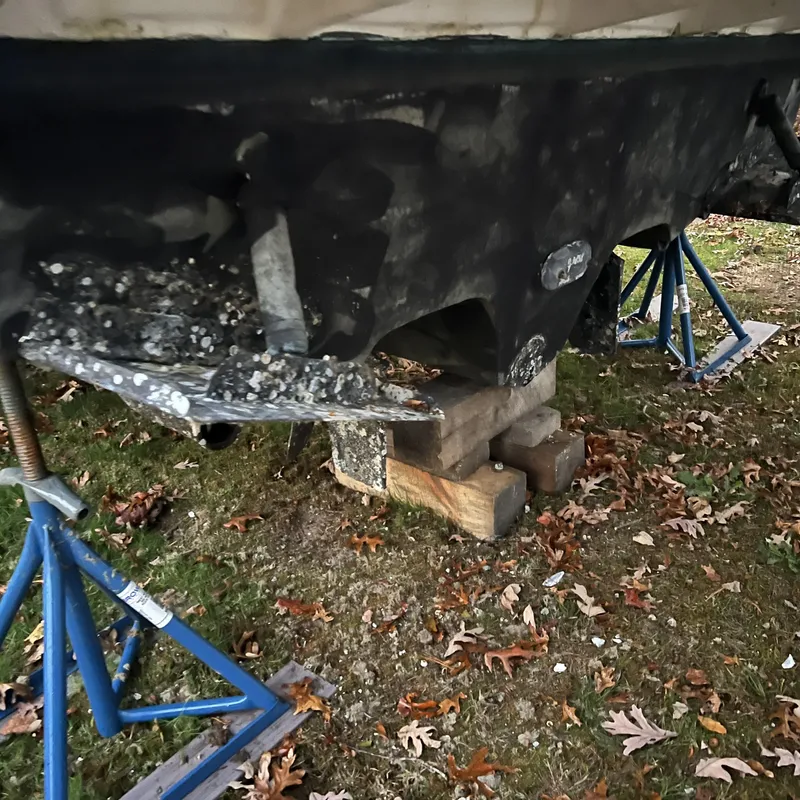 Slide: The Image of 2005 Sea Ray 290 Amberjack hull on stands, showing barnacle growth and support blocks. - 15