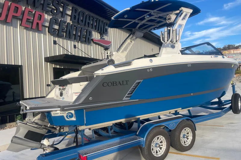 Slide: The Image of 2023 Cobalt R6 Surf boat on trailer at dealership, blue and gray design. - 3