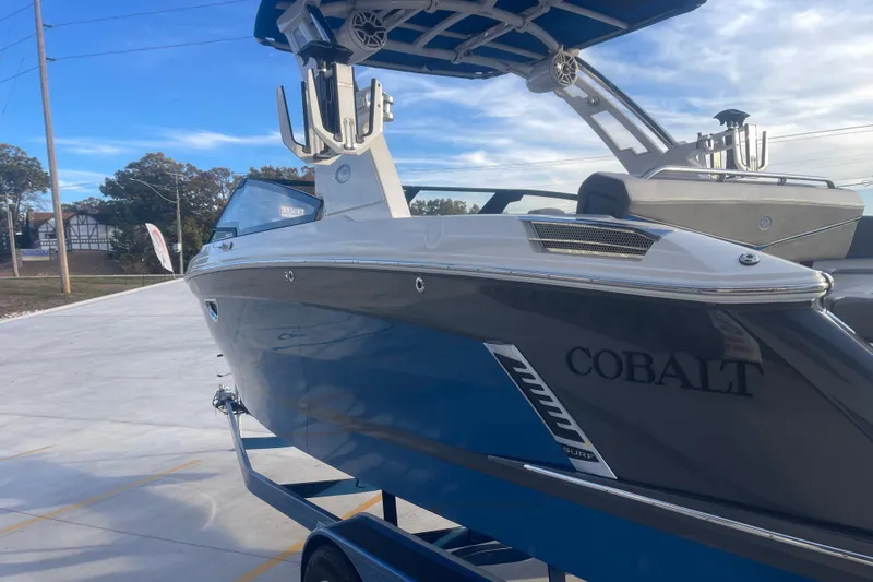 Slide: The Image of 2023 Cobalt R6 Surf boat on trailer, blue and white design, outdoor display. - 9