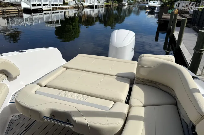 Slide: The Image of 2021 Regal 26 OBX boat with beige seating, docked by a calm waterfront. - 11