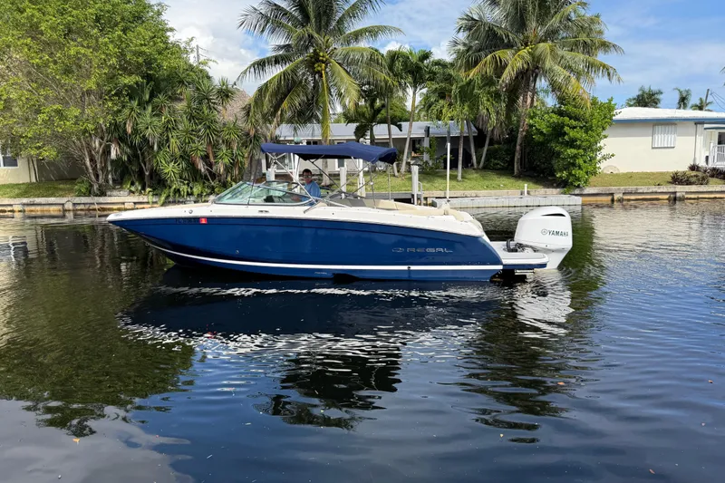 Slide: The Image of 2021 Regal 26 OBX boat on calm water, surrounded by palm trees and houses. - 3