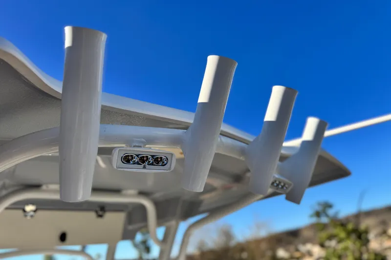 Slide: The Image of 2022 Robalo R222 Center Console boat rod holders against clear blue sky. - 27