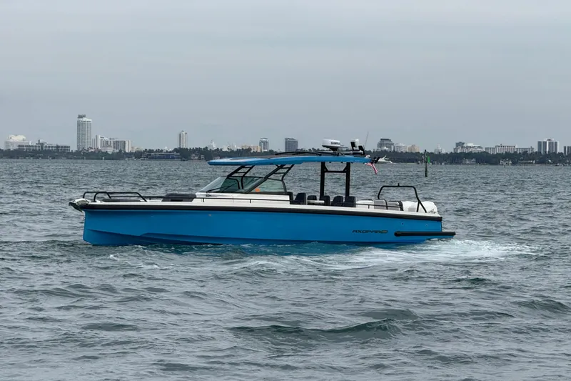 Slide: The Image of 2021 Axopar 37 Sun Top boat cruising on water with city skyline in background. - 10