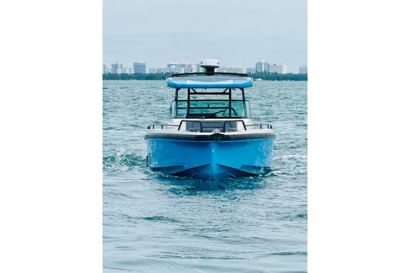 Slide: The Image of 2021 Axopar 37 Sun Top boat cruising on open water with city skyline in background. - 12