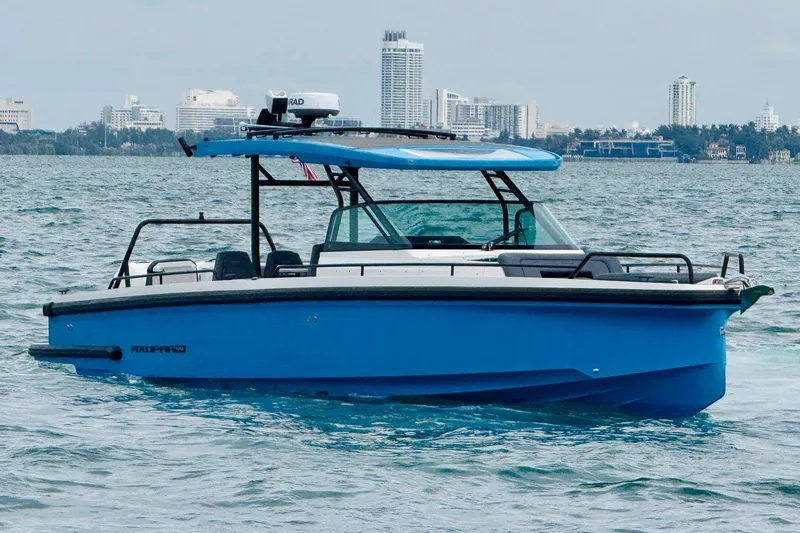 Slide: The Image of 2021 Axopar 37 Sun Top boat on water with city skyline in background. - 2