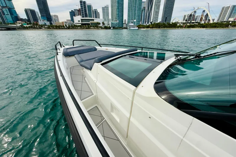 Slide: The Image of 2021 Axopar 37 Sun Top boat on water with city skyline in background. - 24