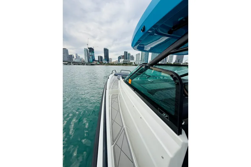 Slide: The Image of Axopar 37 Sun Top 2021 cruising near city skyline on a cloudy day. - 27