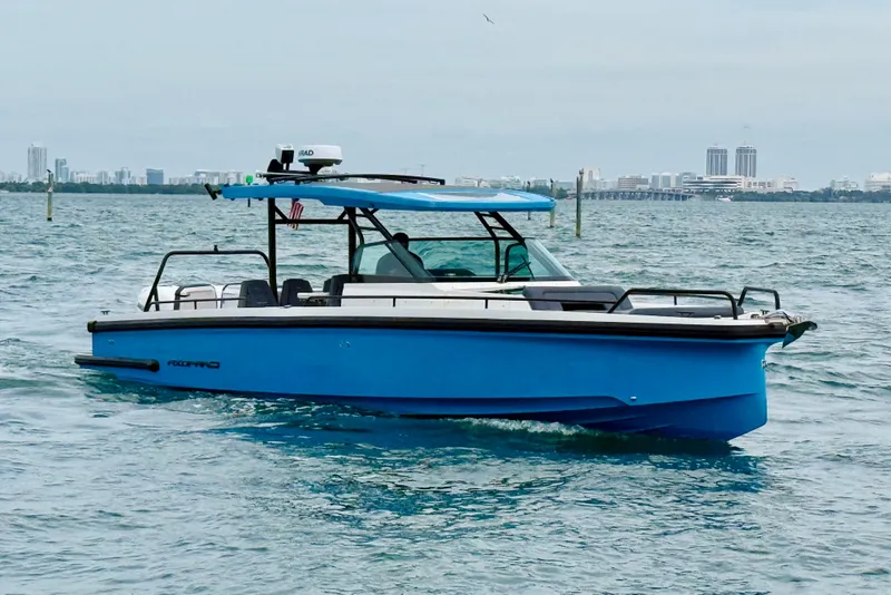 Slide: The Image of 2021 Axopar 37 Sun Top boat cruising on open water with city skyline backdrop. - 3