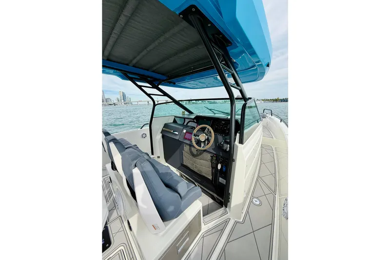 Slide: The Image of 2021 Axopar 37 Sun Top boat interior with helm, blue canopy, and ocean view. - 30