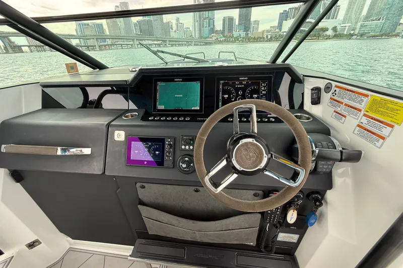 Slide: The Image of 2021 Axopar 37 Sun Top helm with modern navigation system and city skyline view. - 35
