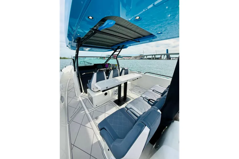 Slide: The Image of 2021 Axopar 37 Sun Top boat interior with seating and table, overlooking water and bridge. - 37