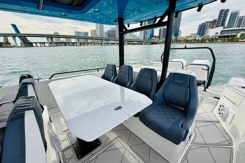 Slide: The Image of 2021 Axopar 37 Sun Top boat interior with seating and table, city skyline view. - 40