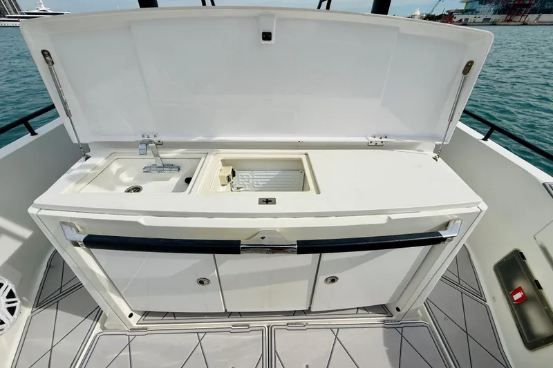 Slide: The Image of 2021 Axopar 37 Sun Top boat kitchenette with sink and storage, docked by the water. - 46