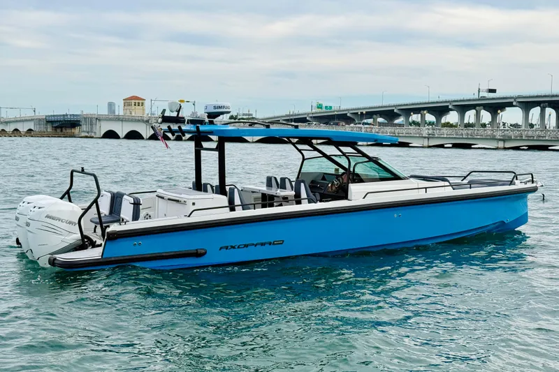 Slide: The Image of 2021 Axopar 37 Sun Top boat on water near a bridge, featuring sleek blue design. - 5