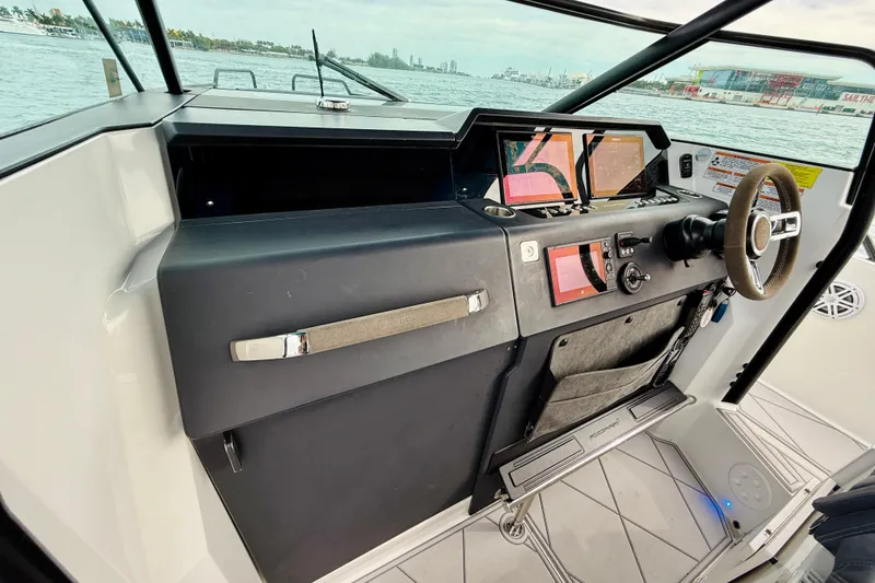 Slide: The Image of 2021 Axopar 37 Sun Top helm with modern controls and navigation screens, docked by the water. - 51