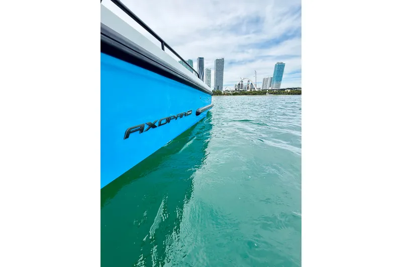Slide: The Image of 2021 Axopar 37 Sun Top boat on turquoise water with city skyline background. - 58