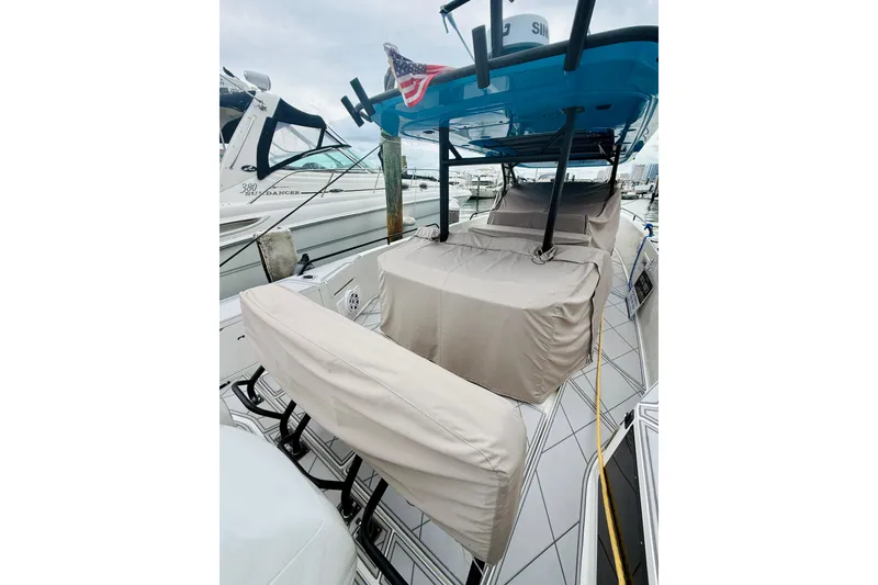 Slide: The Image of 2023 Axopar 37 Sun Top boat with covered seating, docked at a marina. - 62